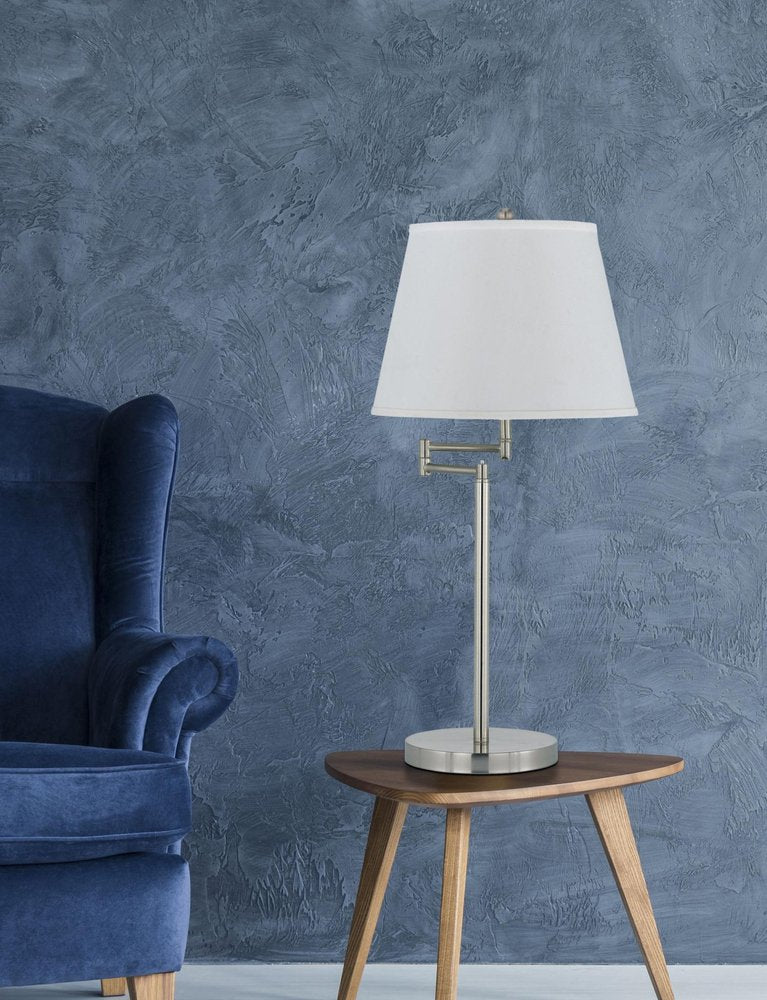 28" Nickel Metal Table Lamp With Off White Empire Shade shown outdoors on an outdoor setting in off-white metal.