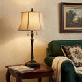31" Black Metal Two Light Candlestick Table Lamp With Beige Empire Shade displayed on a tabletop in a furnished interior against a cream wall.