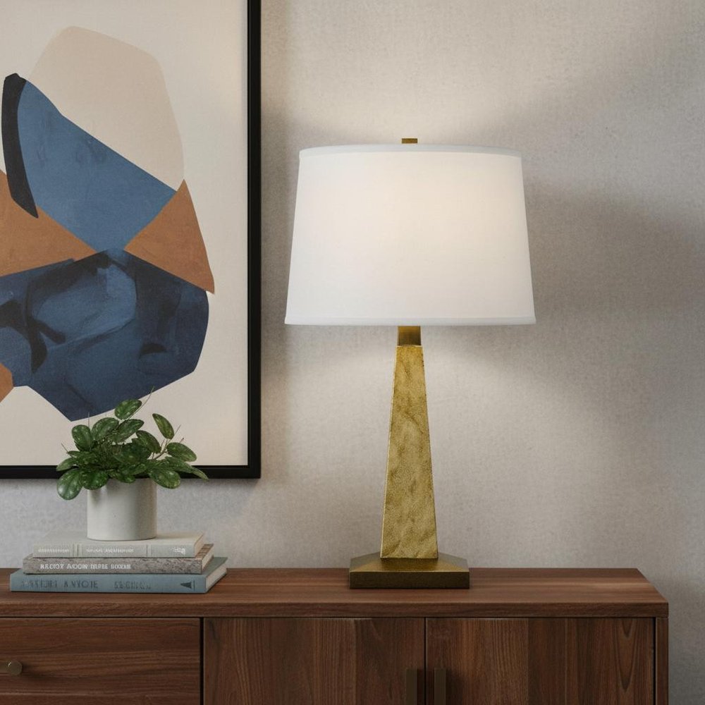 28" Brown Table Lamp With Off White Empire Shade displayed on a dark wood tabletop in a furnished interior against a cream wall in off-white.