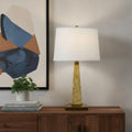 28" Brown Table Lamp With Off White Empire Shade displayed on a dark wood tabletop in a furnished interior against a cream wall in off-white.