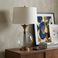 31" Bronze Metal Globe Table Lamp With White Empire Shade displayed on a dark wood tabletop in a furnished interior against a light gray wall.