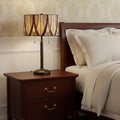 24" Bronze Metal Two Light Table Lamp With Red And Ivory Drum Shade displayed on a tabletop in a furnished interior against a cream wall.