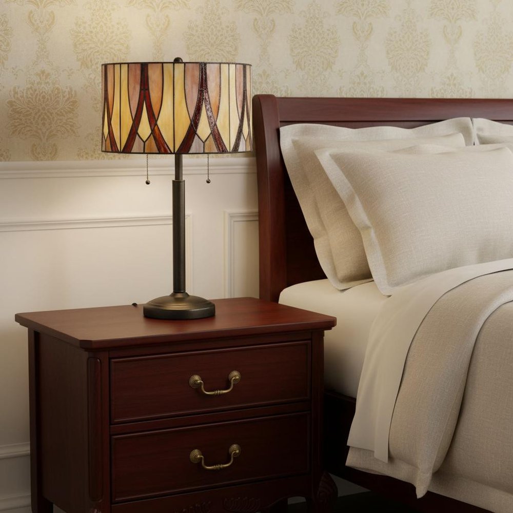 24" Bronze Metal Two Light Table Lamp With Red And Ivory Drum Shade displayed on a tabletop in a furnished interior against a cream wall.