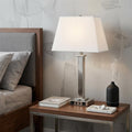 28" Nickel Metal USB Table Lamp With White Shade displayed on a tabletop in a furnished interior against a light gray wall in silver metal.