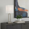 24" Nickel Metal Desk Usb Table Lamp With White Drum Shade displayed on a tabletop in a furnished interior against a light gray wall in silver metal.