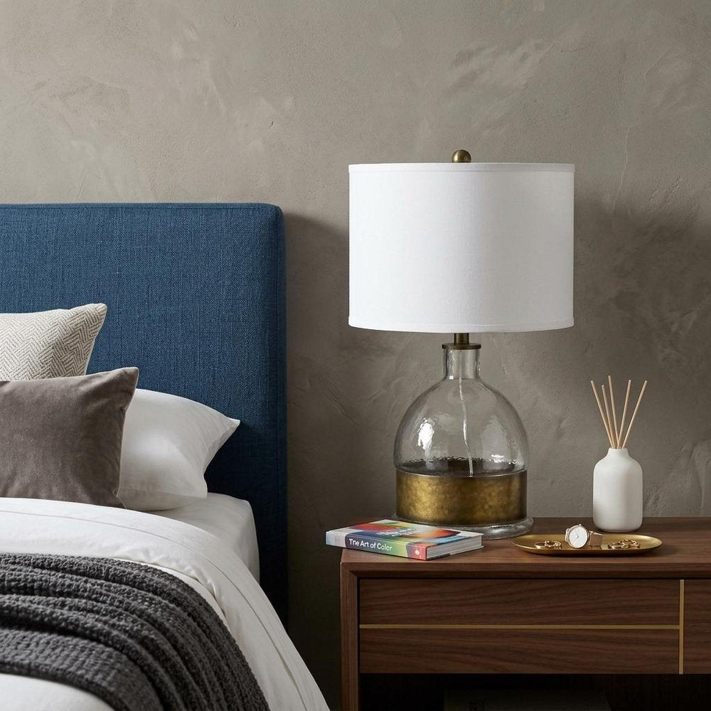 25" Nickel Glass Globe Table Lamp With White Drum Shade displayed on a dark wood tabletop in a furnished interior against a tan wall in silver glass.