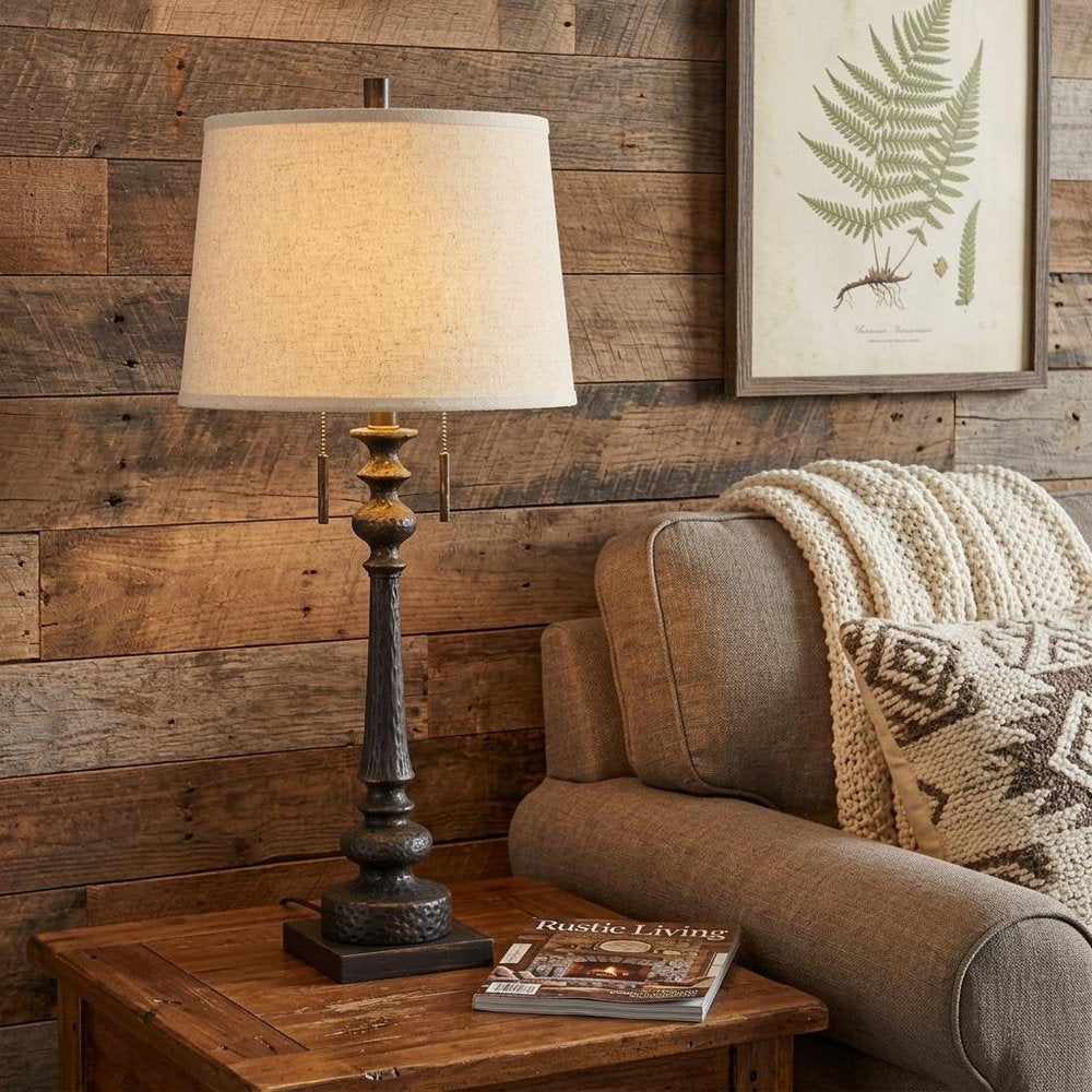 32" Charcoal Two Light Table Lamp With Tan Drum Shade displayed on a dark wood tabletop in a furnished interior against a mahogany wall.