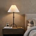 32" Black Metal Table Lamp With Off White Empire Shade displayed on a dark wood tabletop in a furnished interior against a brown wall.