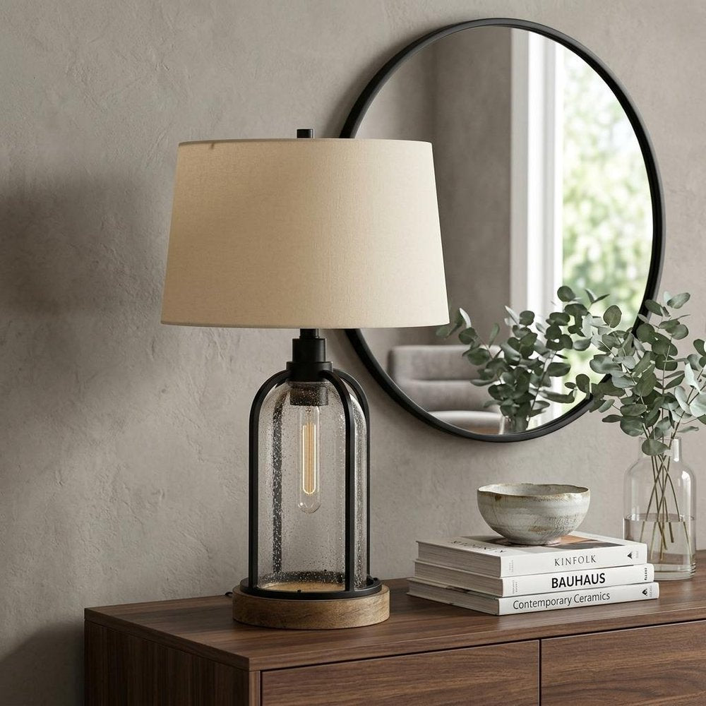 27" Brown Metal Two Light Globe Table Lamp With Eggshell Empire Shade displayed on a dark wood tabletop in a furnished interior against a tan wall.