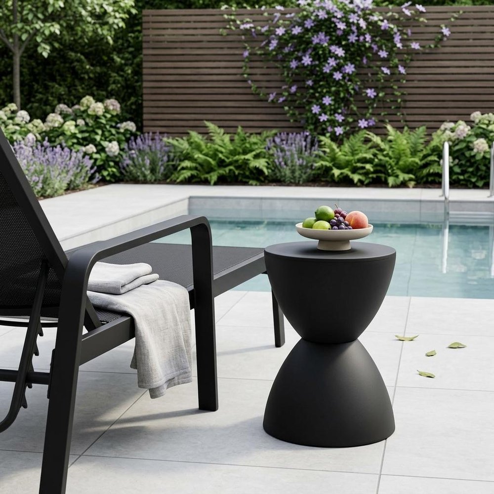 17" Black Heavy Duty Plastic Hourglass Outdoor Side Table shown outdoors on a patio with greenery.