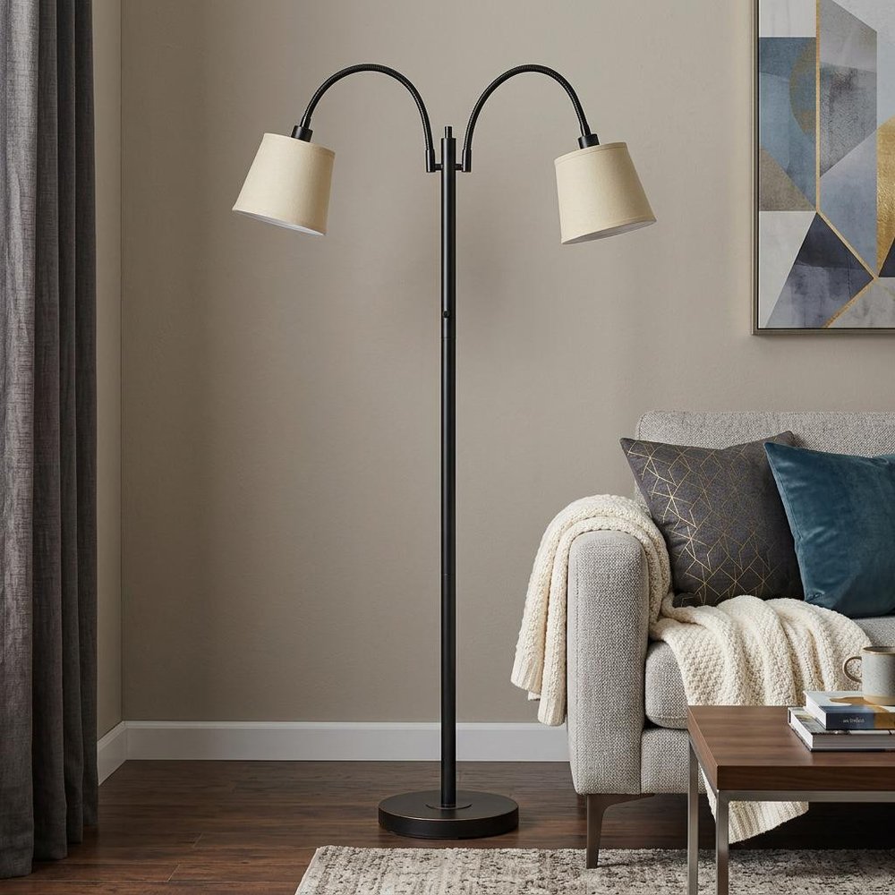 65" Bronze Two Light Traditional Shaped Floor Lamp With Tan Square Shade standing in a furnished interior on a dark wood floor.