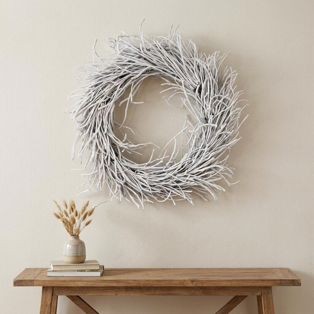 28" White Willow Dried Wreath styled in a furnished interior with an off-white wall on a wood floor.