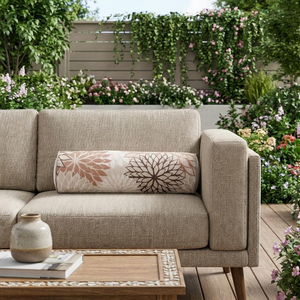 6" X 20" Brown Beige and Ivory Bolster Floral Indoor Outdoor Throw Pillow shown outdoors on a patio with greenery.