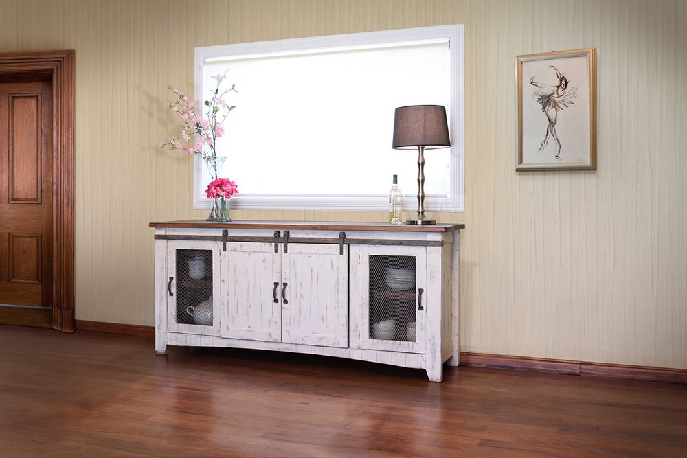 White distressed solid wood cabinet with sliding barn doors and mesh panels, set against a cream-colored wall with a window and wooden floor.