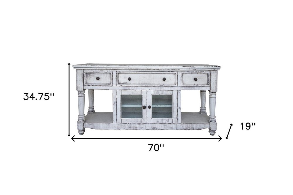 White distressed solid wood TV stand with four drawers, two glass-front cabinets, and open shelving. 70" W x 34.75" H x 19" D.