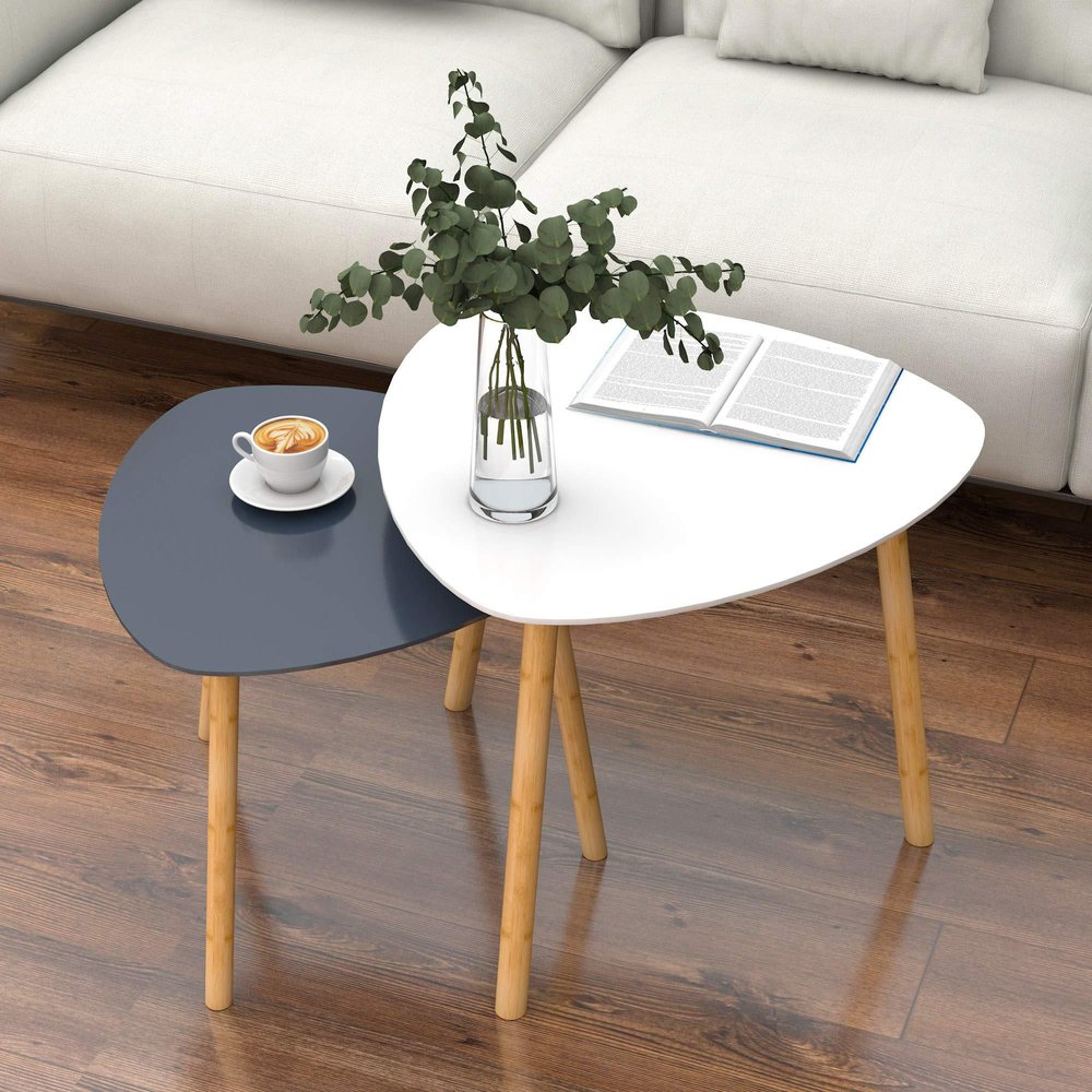 Set of two nested tables, one gray and one white, with wooden legs on a wooden floor next to a white sofa.