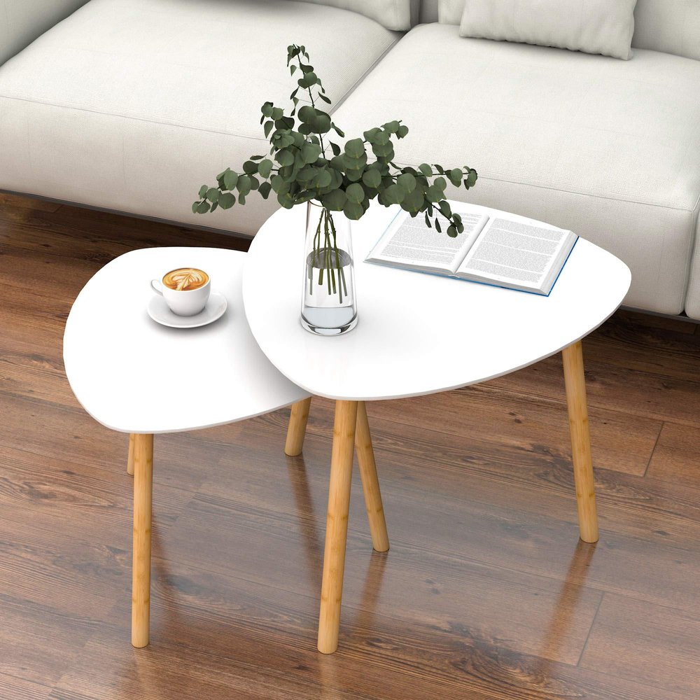 Set of two white triangle nested coffee tables with natural wood legs on a wood floor next to a white sofa.