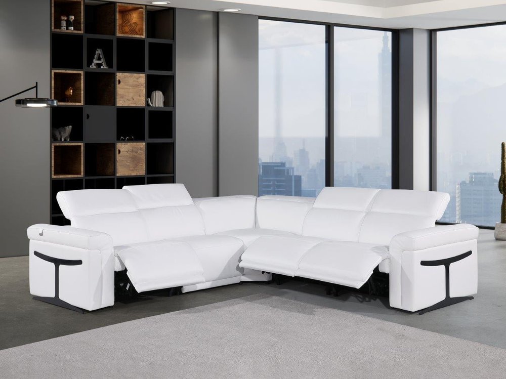 White Italian leather L-shaped sectional sofa with reclining seats in a modern living room with large windows.