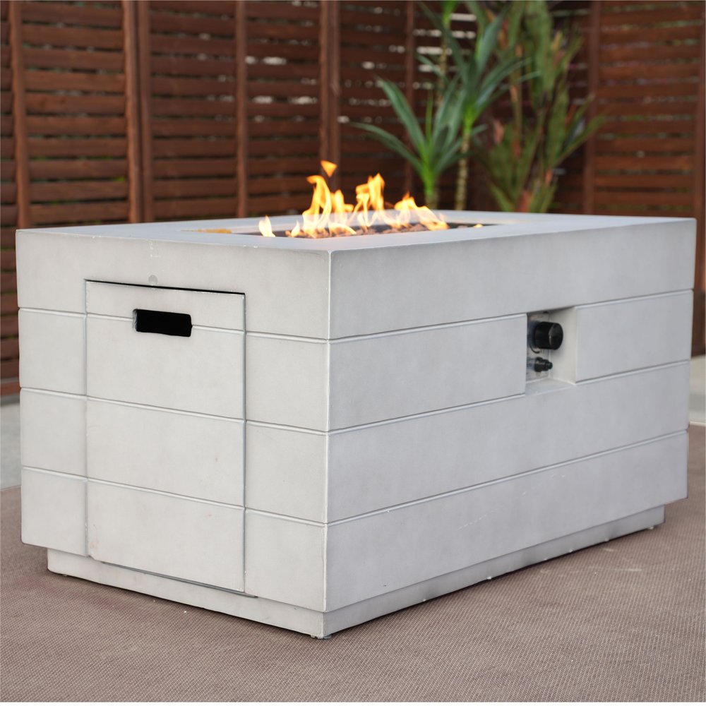 28" Gray Aluminum Natural gas Rectangular Fire pit table With Cover styled in a furnished interior with a dark brown wall on a wood floor.