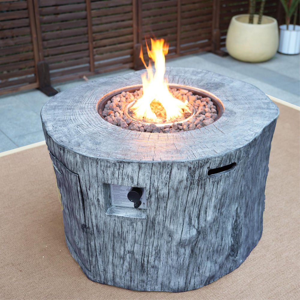 50000 BTU 40" Gray Aluminum Natural Gas Round Fire Pit Table With Cover styled in a furnished interior with a dark wall on a wood floor.
