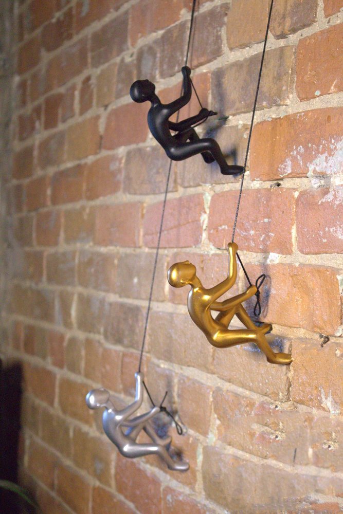 Set of Two Silver Resin Climbing Man Hanging Dimensional Sculpture in a home interior
