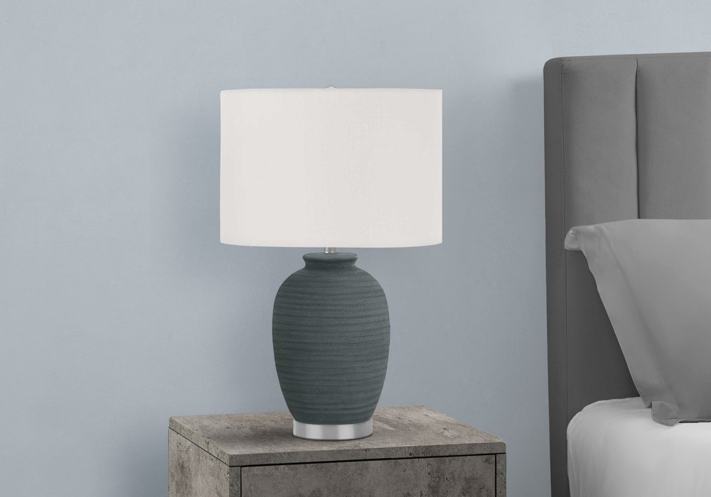 24" Blue and Silver Ceramic Round Table Lamp With Ivory Drum Shade. Table lamp isolated on a plain white background, showing a silver ceramic surface.