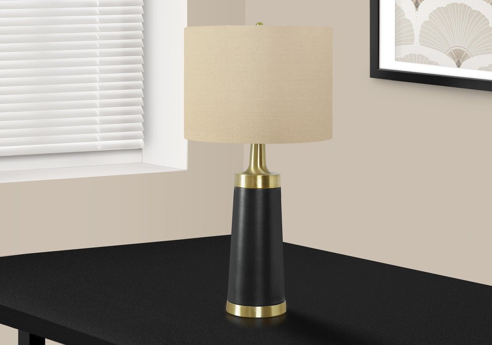 28" Black and Gold Metal Cylinder Table Lamp With Beige Drum Shade photographed against a dark studio background in beige.