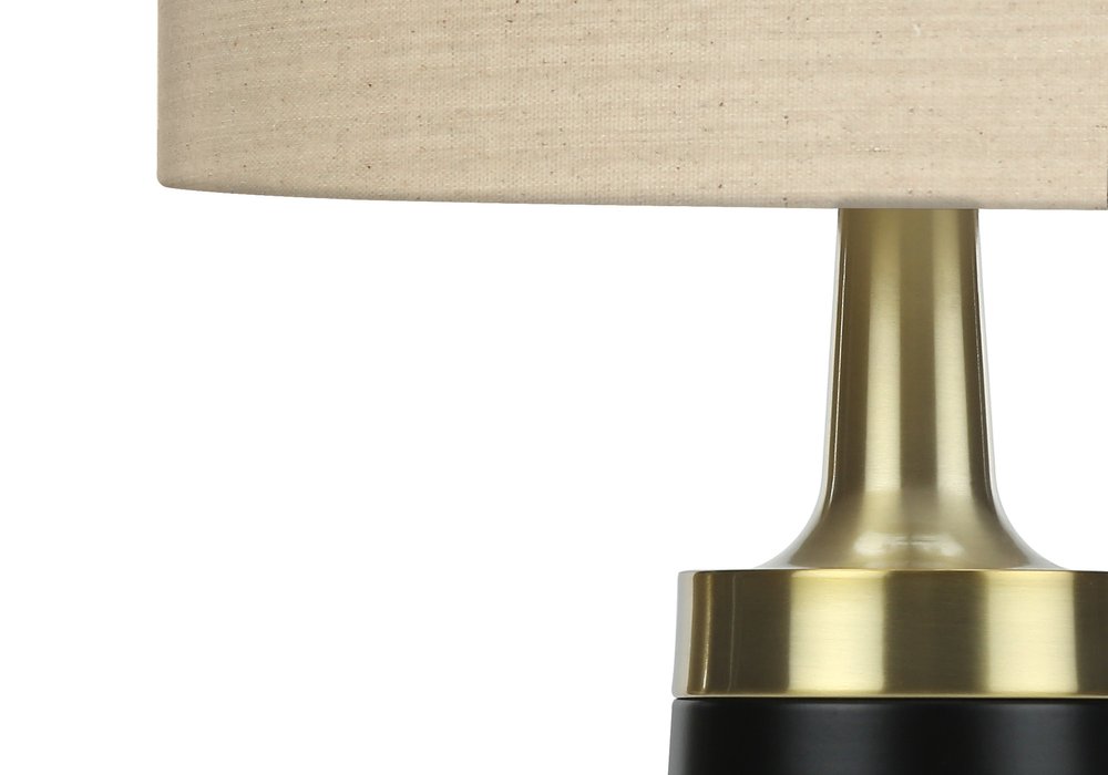28" Black and Gold Metal Cylinder Table Lamp With Beige Drum Shade. Table lamp isolated on a plain white background, showing a beige metal surface.