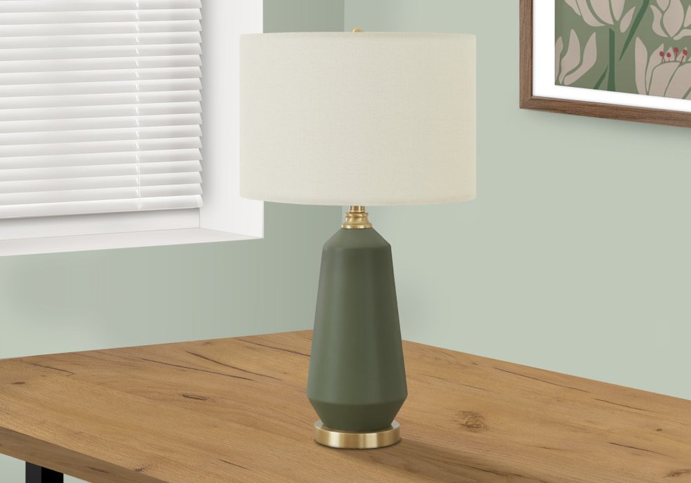 26" Green Ceramic Geometric Table Lamp With Ivory Drum Shade displayed on a wood tabletop in a furnished interior against an off-white wall.