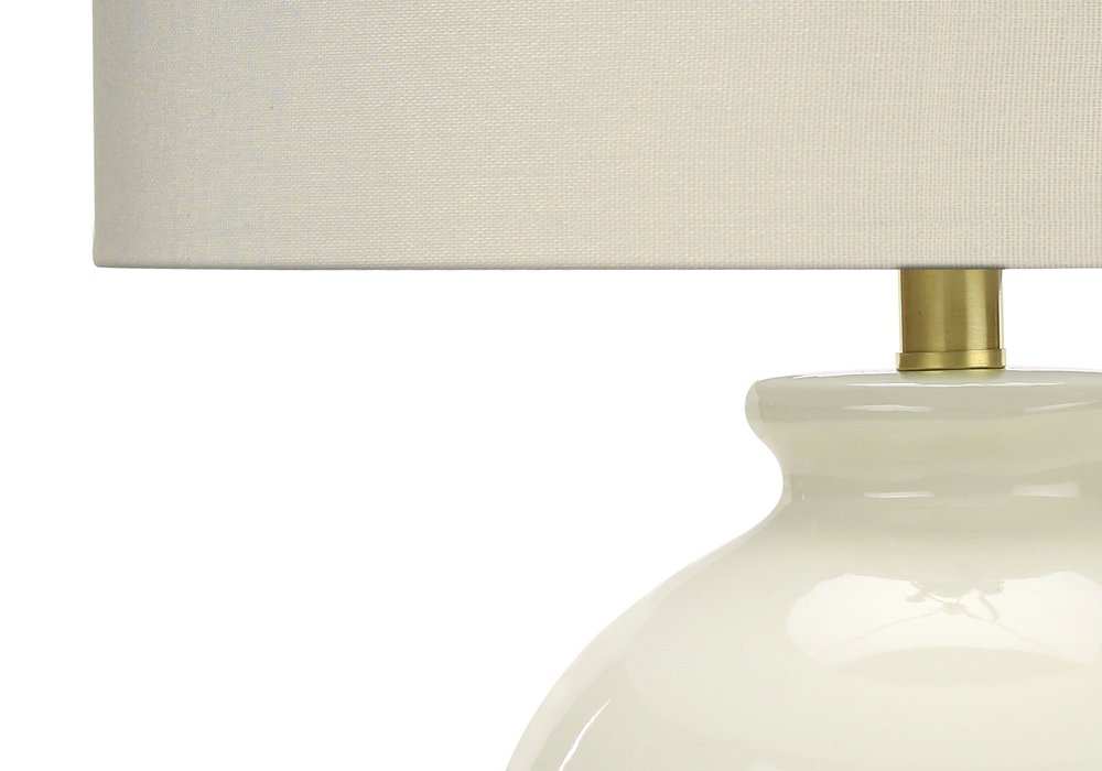 26" Gold and Ivory Ceramic Urn Table Lamp With Cream Drum Shade. Table lamp isolated on a plain white background, showing a ivory ceramic surface.