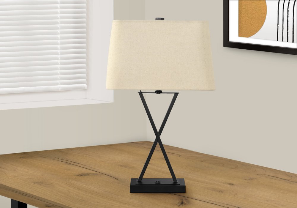 25" Black Metal Geometric USB Table Lamp With Beige Shade displayed on a wood tabletop in a furnished interior against an off-white wall.