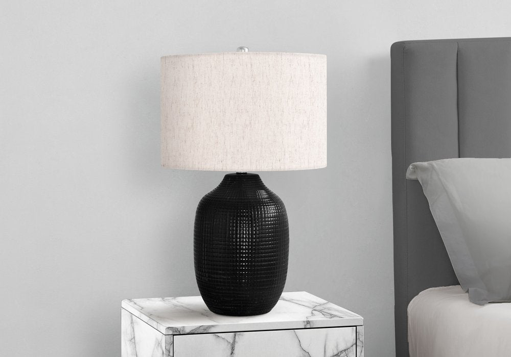 26" Black Ceramic Urn Table Lamp With Ivory Drum Shade. Table lamp isolated on a plain white background, showing a ivory ceramic surface.