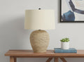 25" Beige Rattan Round Table Lamp With Beige Drum Shade displayed on a tabletop in a furnished interior against an off-white wall.