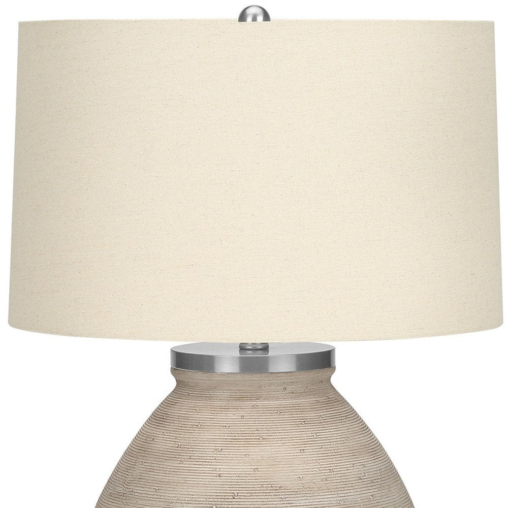 25" Cream Concrete Round Table Lamp With Beige Drum Shade. Table lamp isolated on a plain white background, in a cream finish.