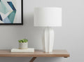 27" Cream Ceramic Geometric Table Lamp With Cream Drum Shade displayed on a tabletop in a furnished interior against an off-white wall.