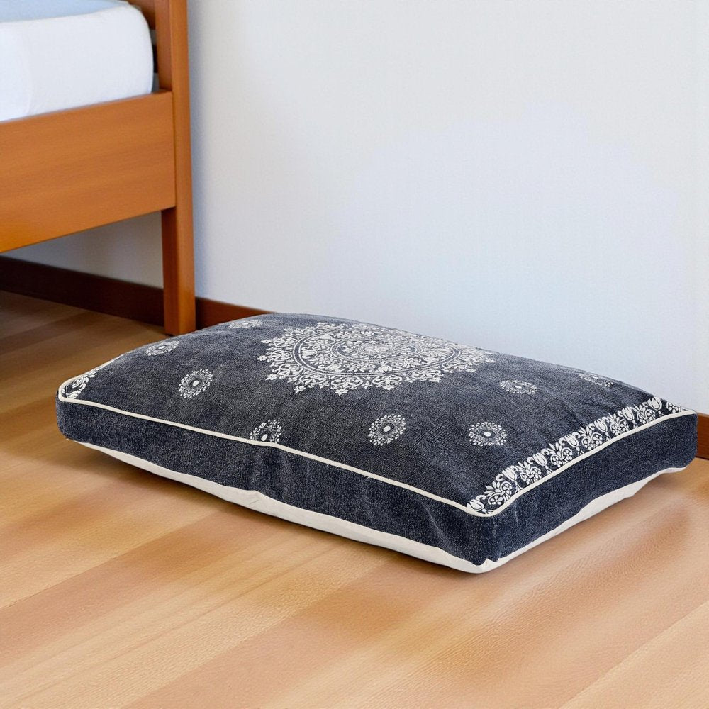 24" X 36" Stonewashed Blue Medallion Pillow Style Pet Bed With Removable Cover styled in a furnished interior with an off-white wall on the floor.