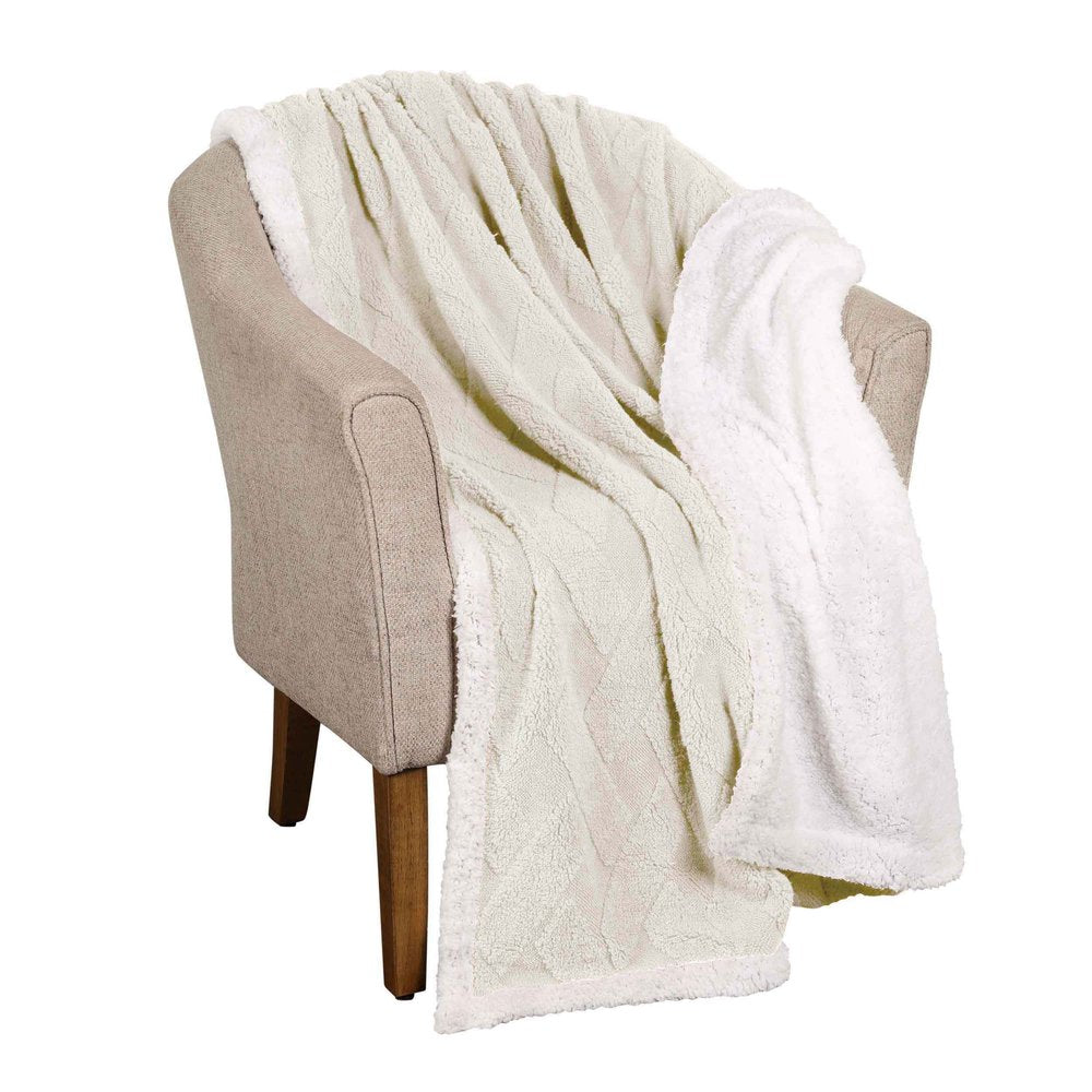 Ivory fleece geometric plush blanket draped over a tan armchair.