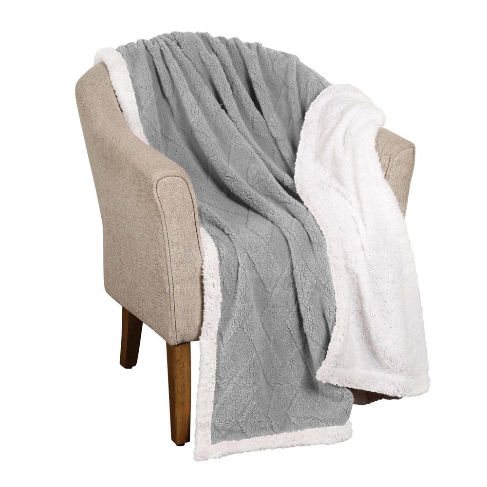 A gray and white plush fleece knitted blanket draped over a beige armchair.