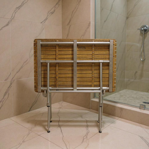 Brown teak rectangular shower bench with silver metal legs in a tiled bathroom with a shower stall.