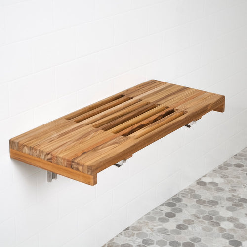 Wall-mounted teak shower bench with slatted top in a bathroom with white subway tile and hexagonal floor tiles.