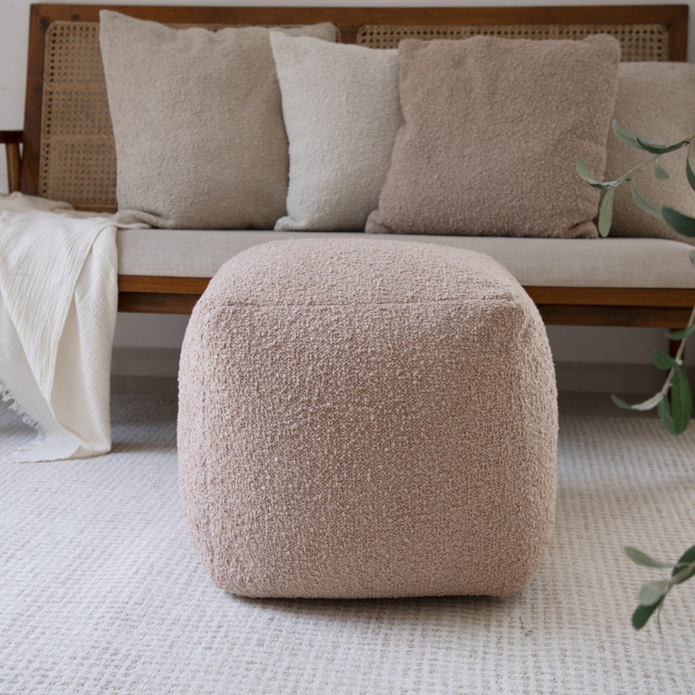 18" Beige Polyester Cube Outdoor Pouf Ottoman styled in a furnished interior with a dark brown wall on a tiled floor.