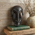 10" Black Solid Wood Decorative Mask Tabletop Sculpture styled in a furnished interior with a tan wall on a wood floor.