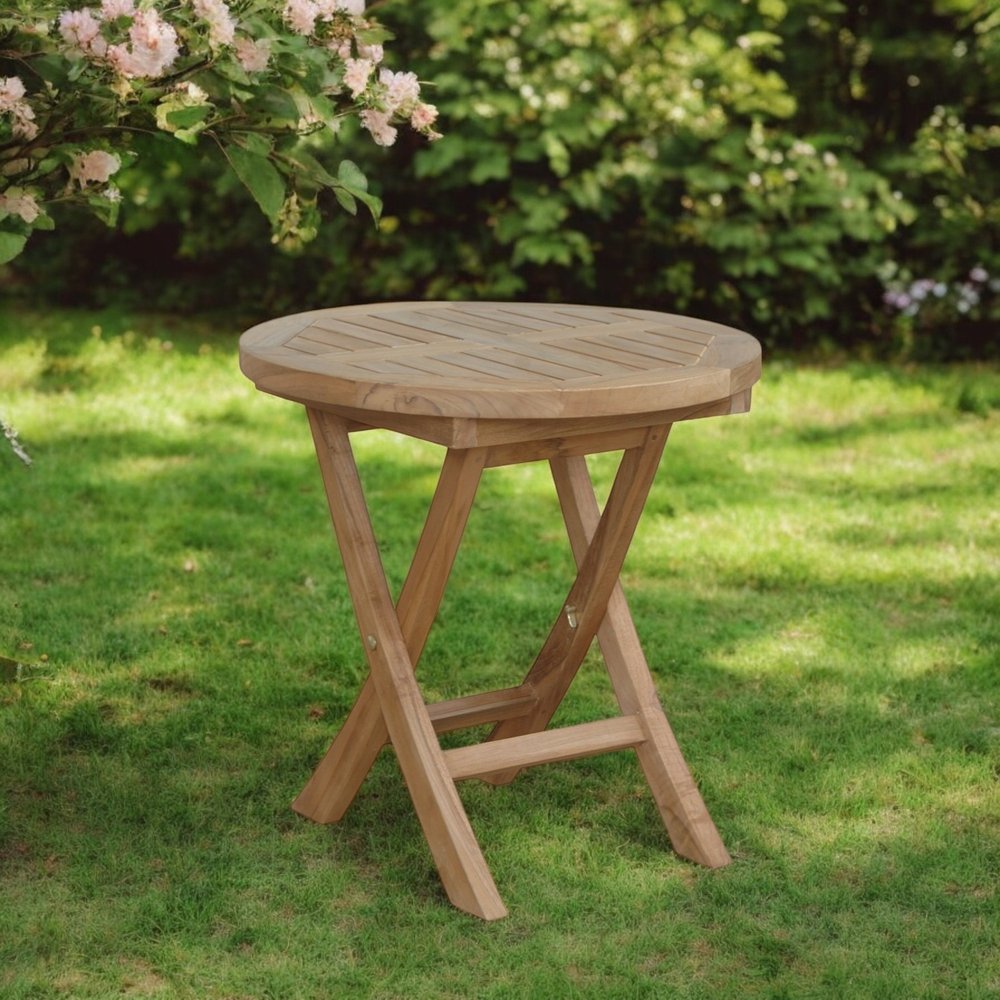 20" Natural Rounded Solid Wood Folding Outdoor Side Table - SKU 554936 shown outdoors on a patio with greenery.