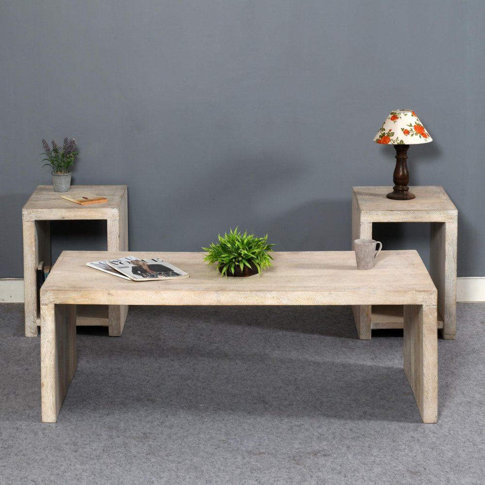 A three-piece natural distressed solid wood coffee and end tables set against a gray wall and gray carpet.