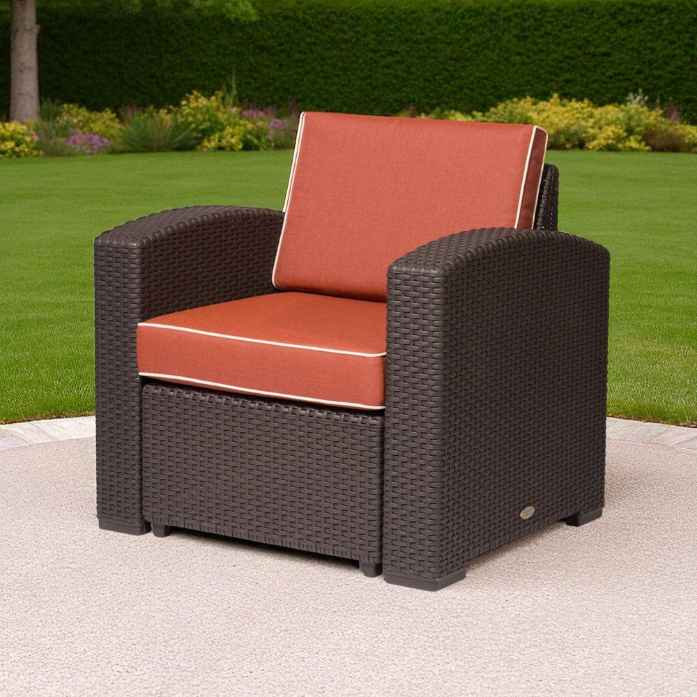 33" Red Heavy Duty Plastic Outdoor Accent Chair with Red Cushion shown outdoors on a patio with greenery.