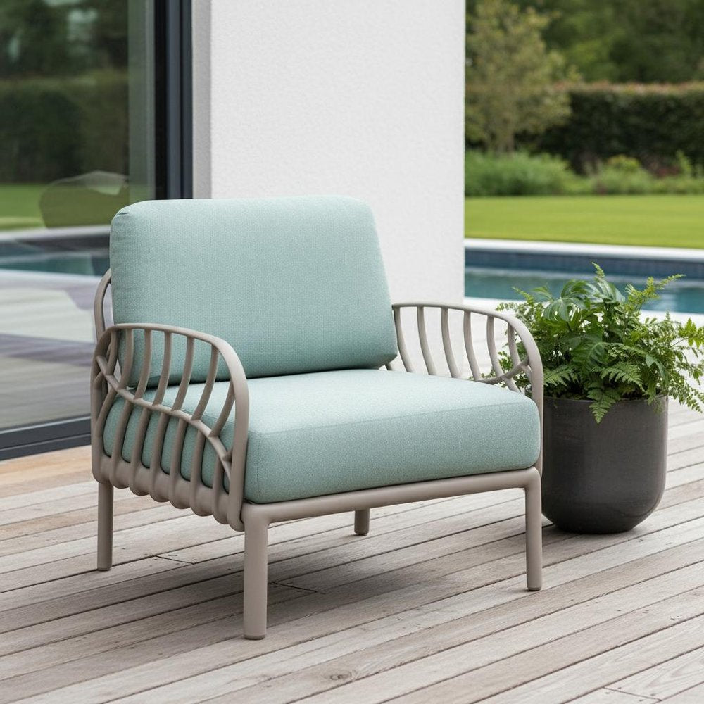 31" Gray Heavy Duty Plastic Outdoor Armchair With Sea Green Cushion shown outdoors on a tiled patio with greenery.