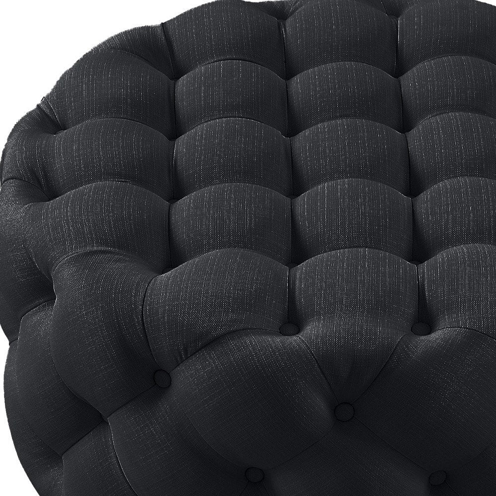 33" Black Linen Tufted Round Cocktail Ottoman photographed against a dark studio background in black.