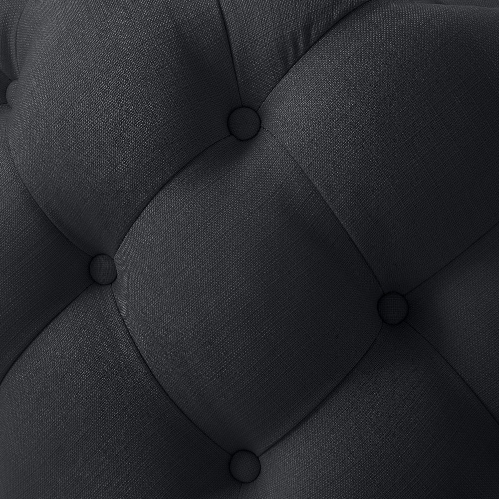 Close-up of a black linen tufted round cocktail ottoman with diamond-shaped tufting.