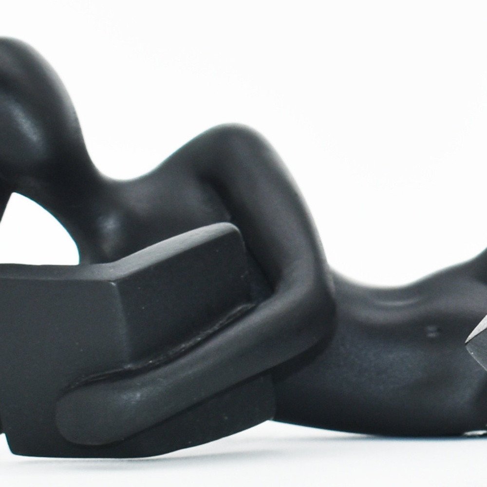 Black resin sculpture of two abstract figures holding a rectangular object, on a white background.