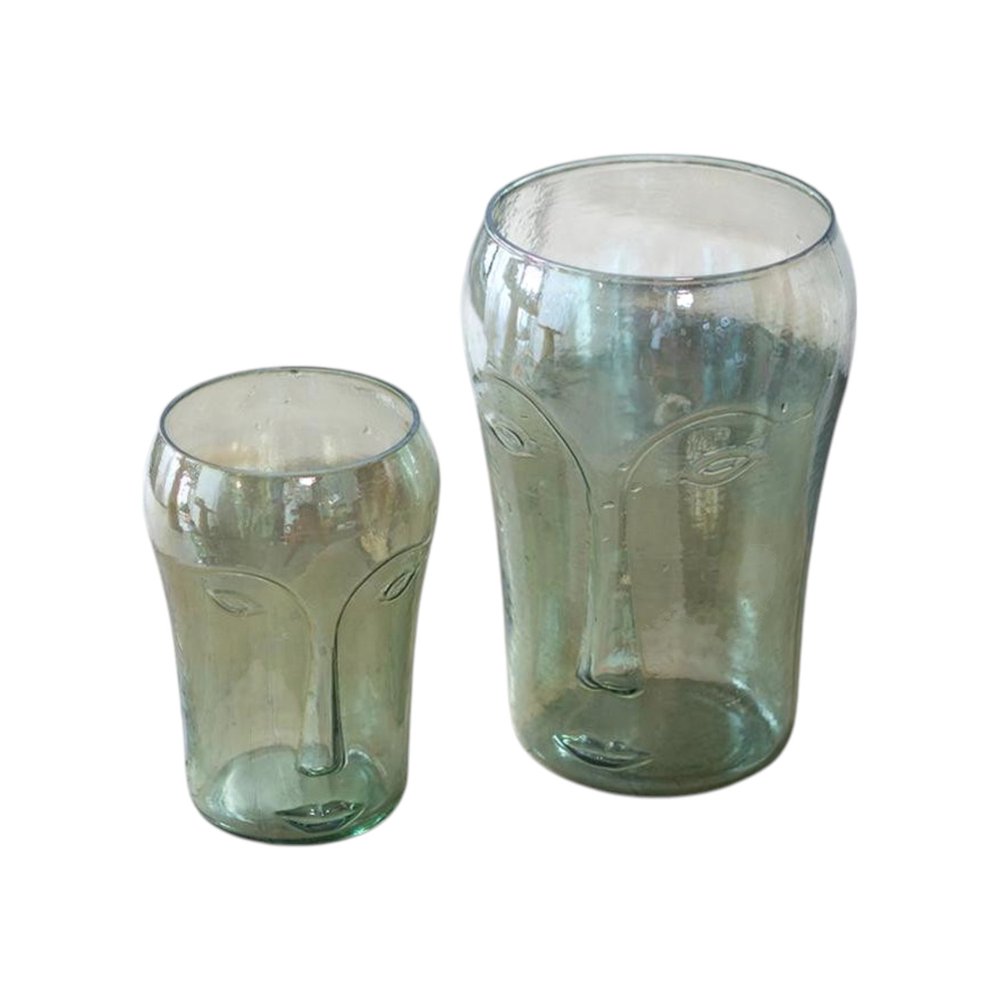 Two light green glass vases with abstract face designs on a white background.